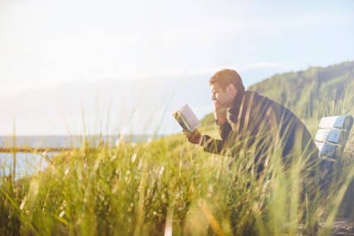 Un homme qui lit au milieu de la verdure