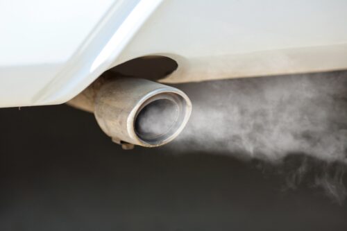 De la fumée sort d'un pot d'échappement, contribuant à la pollution de l'air.