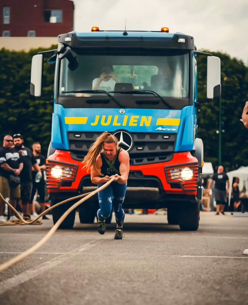 épreuve de strongman : Une athlète tire un camion à l'aide de ses bras.