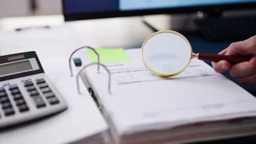 Une loupe sur un livre de comptes.