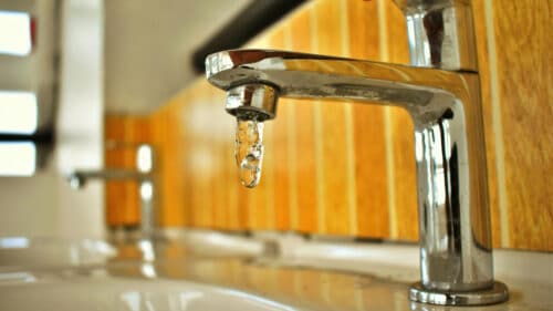 Un robinet ouvert, de l'eau coule.