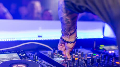 Focus sur la main d'un DJ sur une table de mixage.